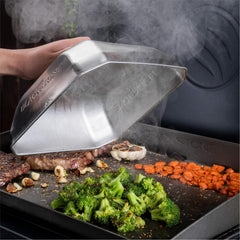 Blackstone tapa en uso sobre plancha con verduras vaporidas uniformemente