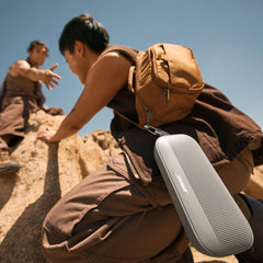 Bose SoundLink Flex colgado de una mochila con correa, facilita transporte en exteriores