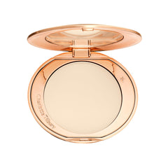 Charlotte Tilbury polvo compacto en su estuche mostrando el diseño elegante y beneficio de portabilidad
