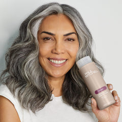 Botella Paul Mitchell Extra-Body junto a una mano para comparar tamaño y capacidad práctica