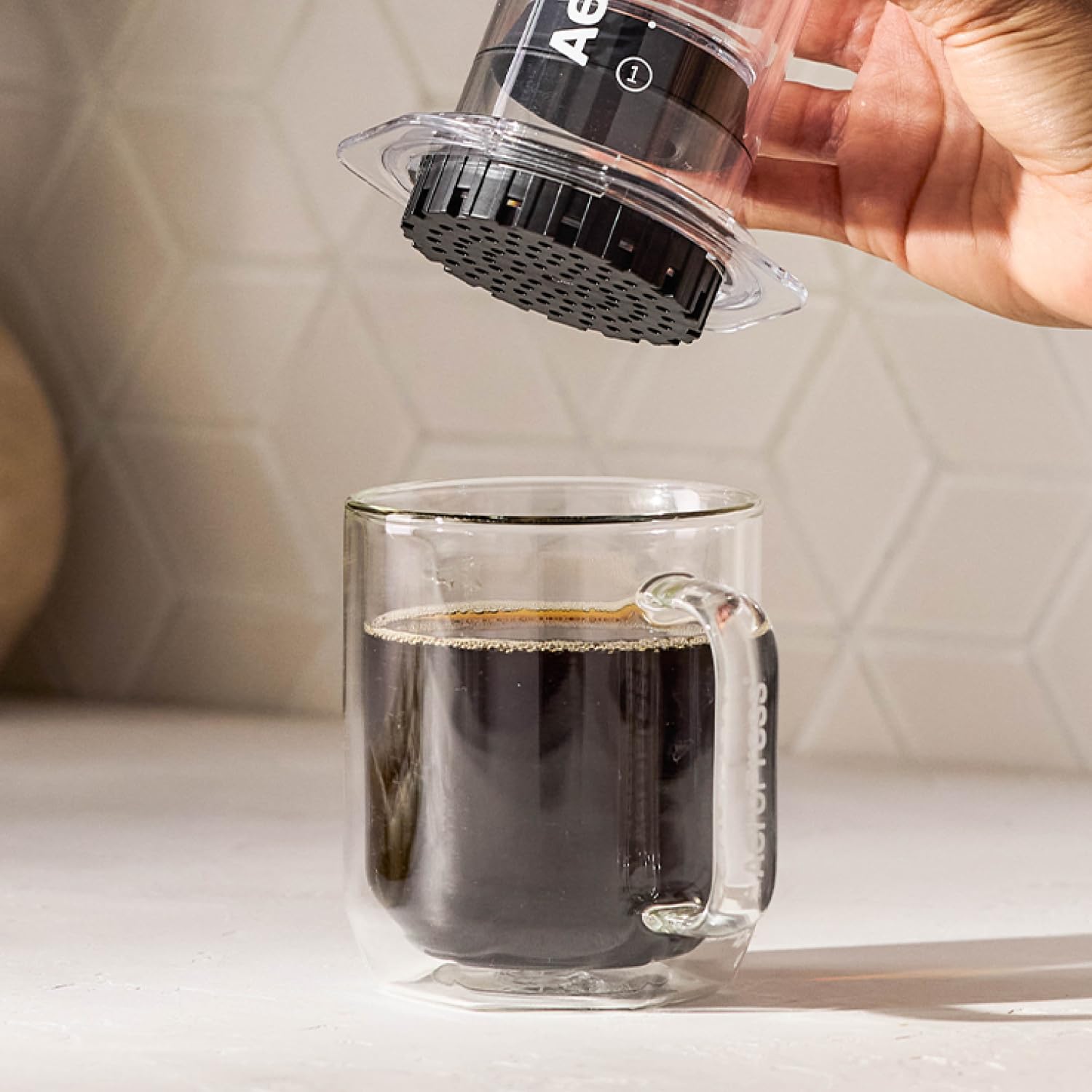 AeroPress empaque sostenido en mano para mostrar tamaño y ahorro por lote