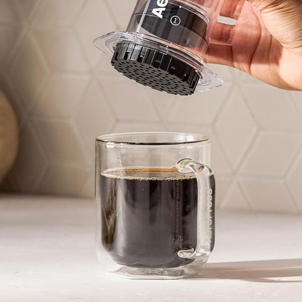 AeroPress empaque sostenido en mano para mostrar tamaño y ahorro por lote