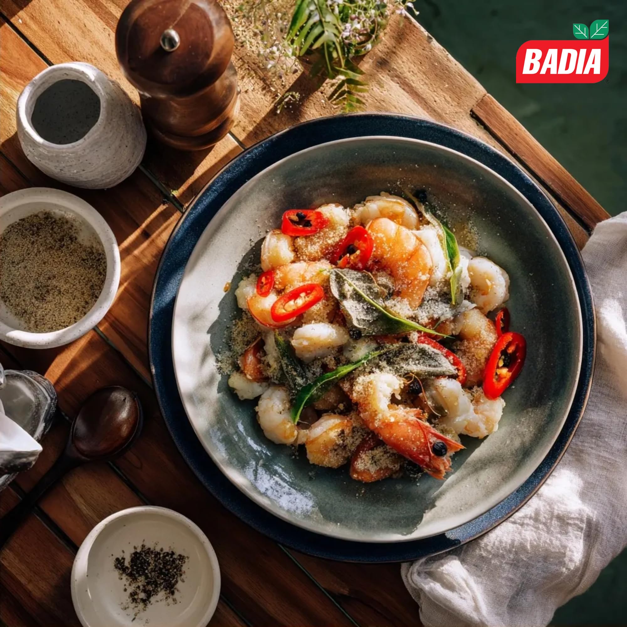 Cocinero espolvoreando Badia pimienta blanca en salsa clara