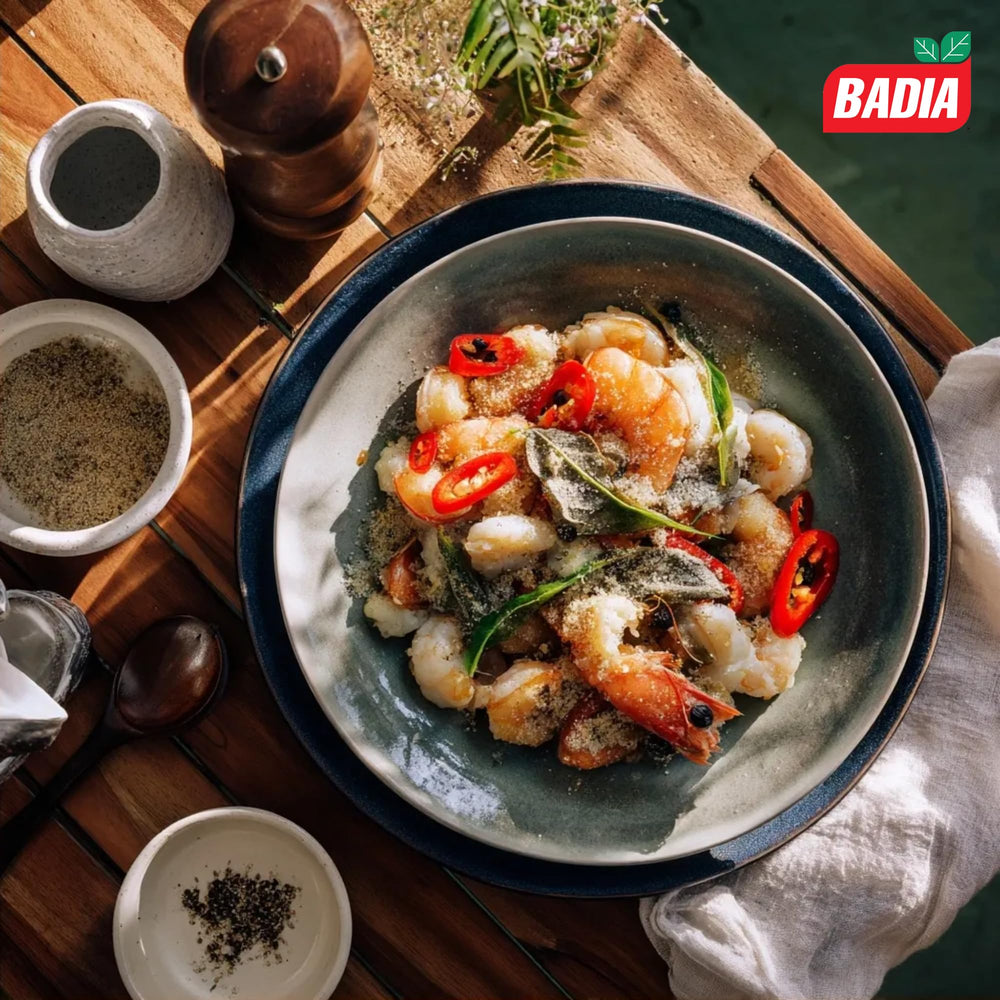 Cocinero espolvoreando Badia pimienta blanca en salsa clara