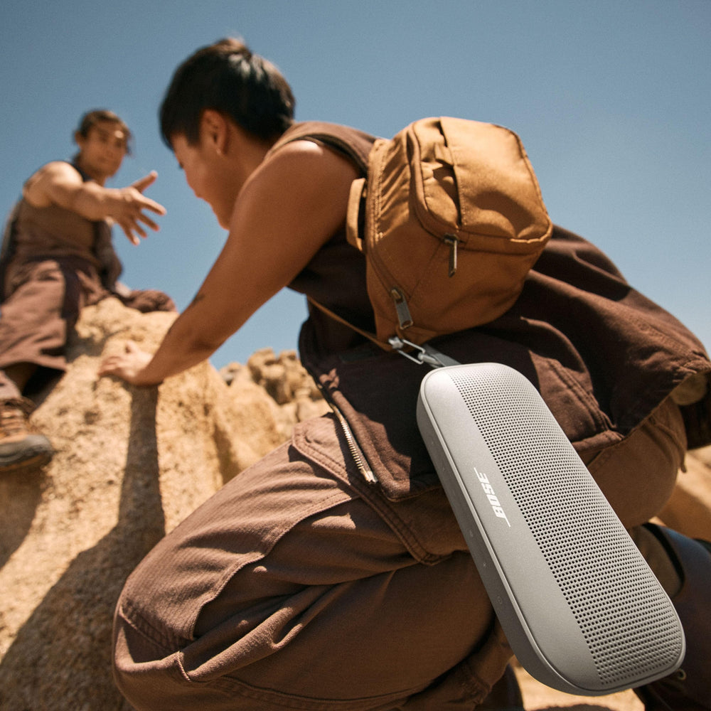 Bose SoundLink Flex colgado de una mochila con correa, facilita transporte en exteriores