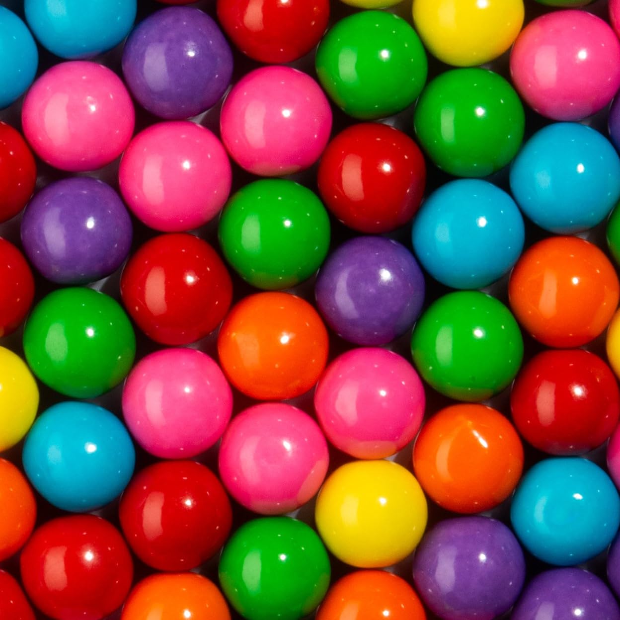 Candy Envy gumball junto a mano para comparar el tamaño de 1 pulgada y porciones