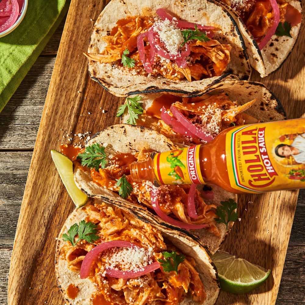 Cholula junto a chiles y limones mostrando usos culinarios versátiles