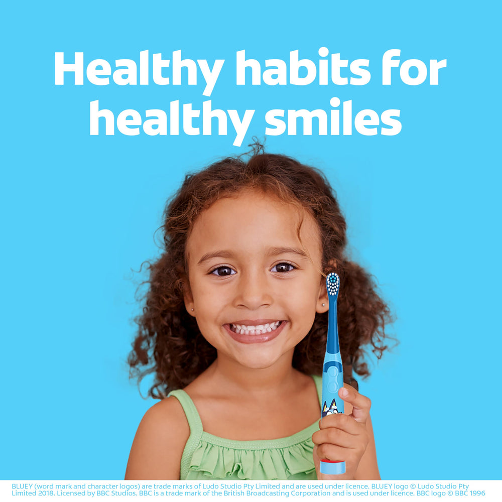 Colgate Bluey comparación de tamaño del cepillo frente a una mano infantil