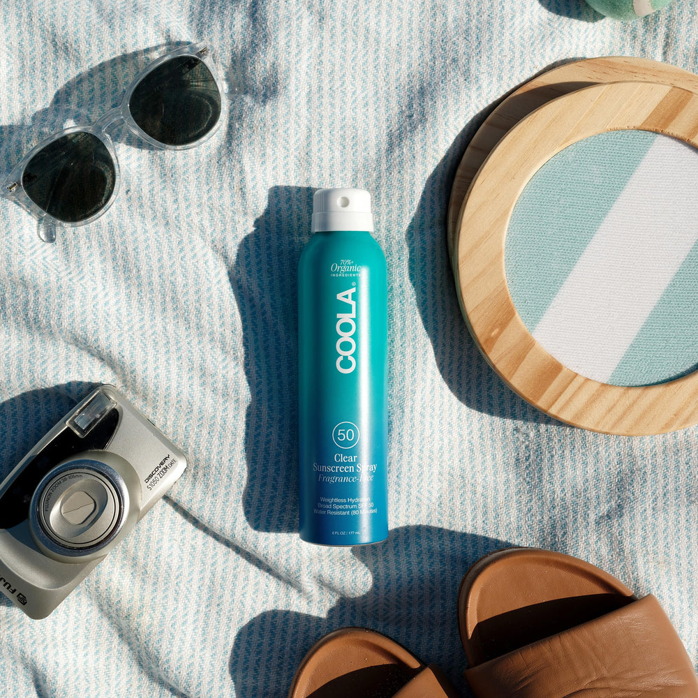 Persona aplicando COOLA en la playa para protección SPF 50 durante actividades