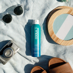 Persona aplicando COOLA en la playa para protección SPF 50 durante actividades