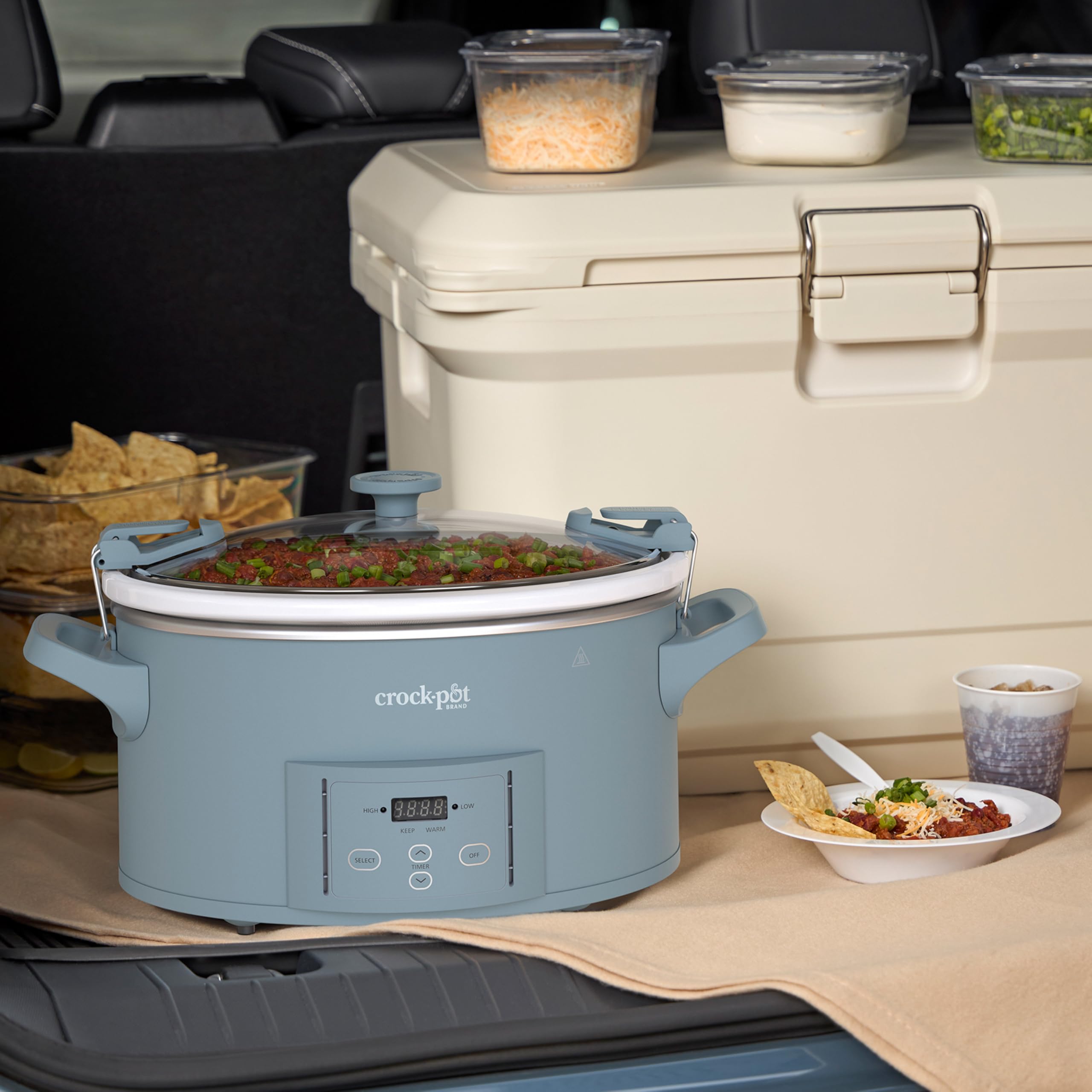 Manos transportando Crock-Pot con asas resistentes y tapa cerrada