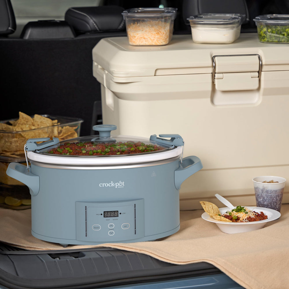 Manos transportando Crock-Pot con asas resistentes y tapa cerrada