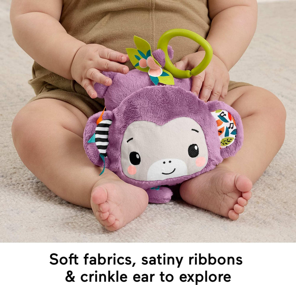 Fisher-Price mono junto a una mano de adulto para comparar tamaño y portabilidad