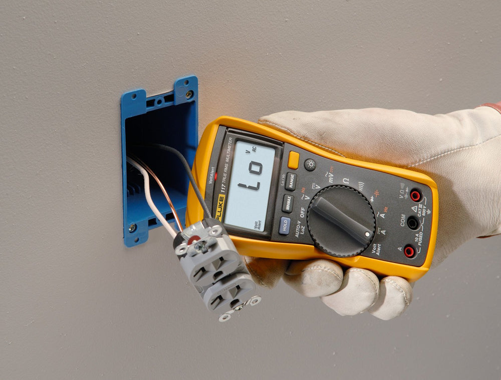 Fluke 117 junto a una mano para comparar tamaño y portabilidad