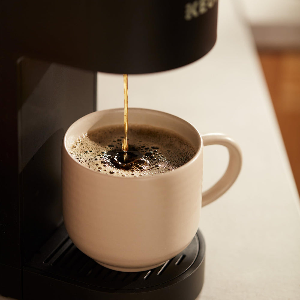 Folgers cápsula en mano para comparar tamaño y portabilidad fácil