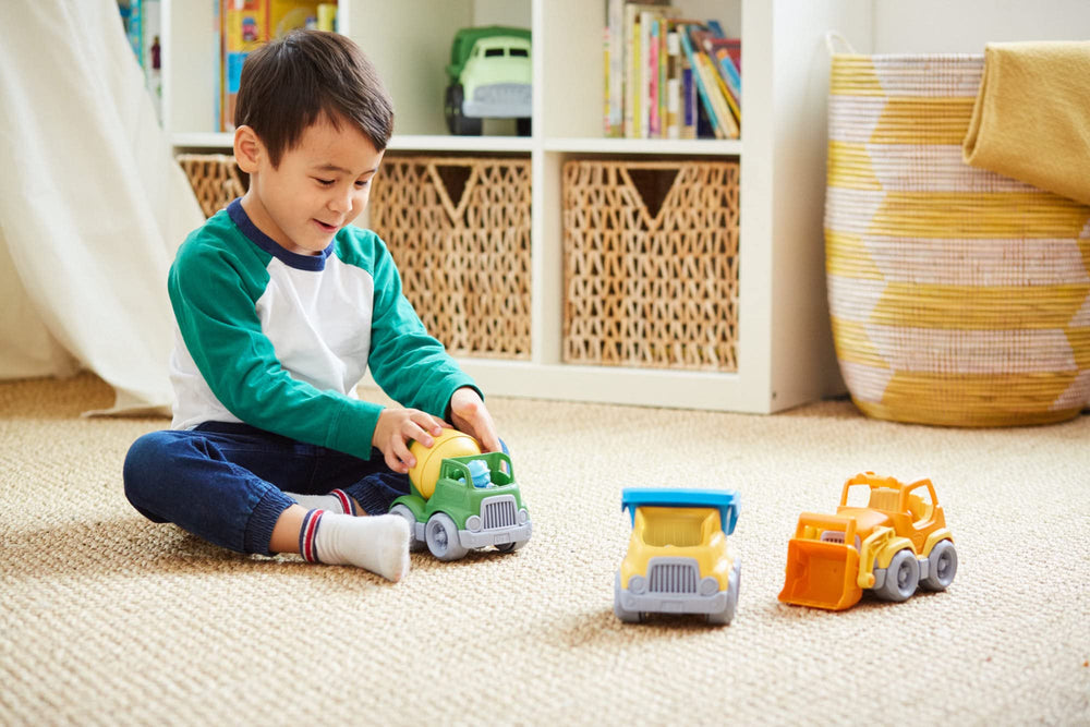 Green Toys camiones junto a una mano para mostrar escala y manejo fácil