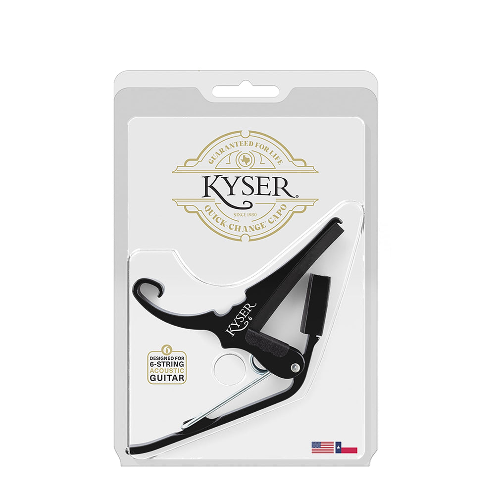 Kyser KG6BA beside guitar picks for scale, showing compact travel-friendly size
