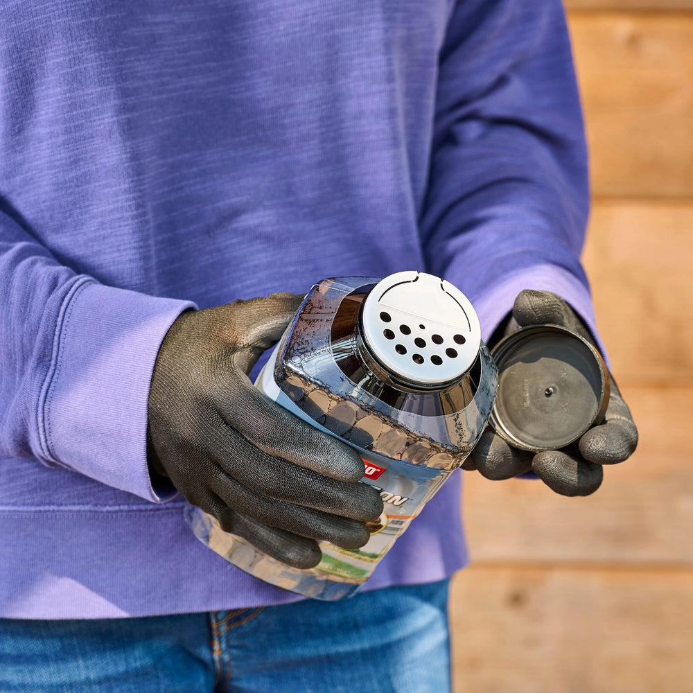 Lifestyle yard image with Ortho bottles near lawn and garden demonstrating setup