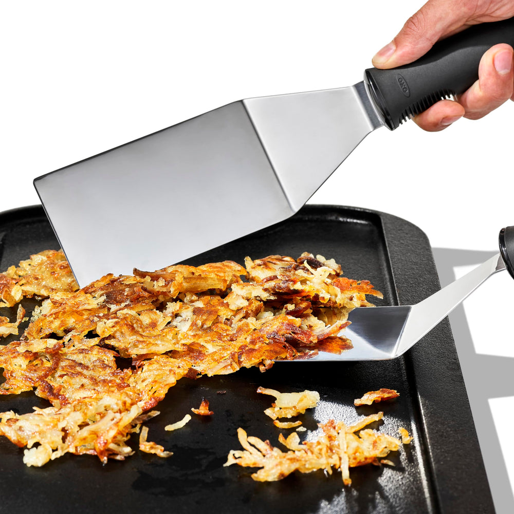 OXO espátula levantando hamburguesa en plancha para uso profesional