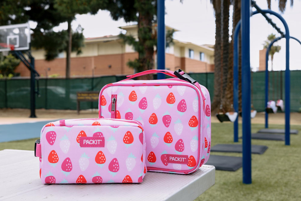 PackIt lonchera plegada junto a objetos para comparar tamaño compacto