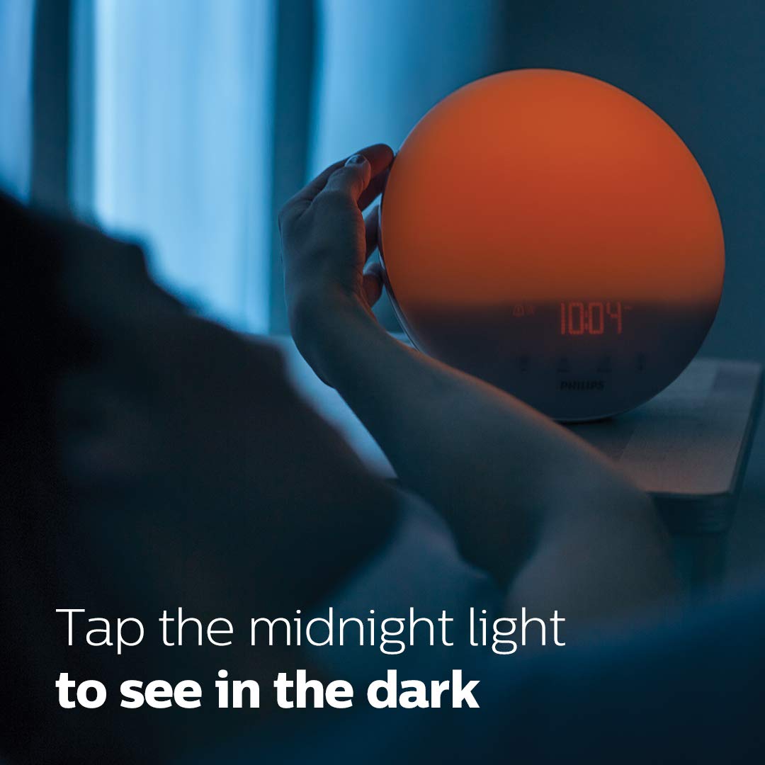 Philips SmartSleep junto a un libro y teléfono para comparar tamaño y escala, compacto en cabecera