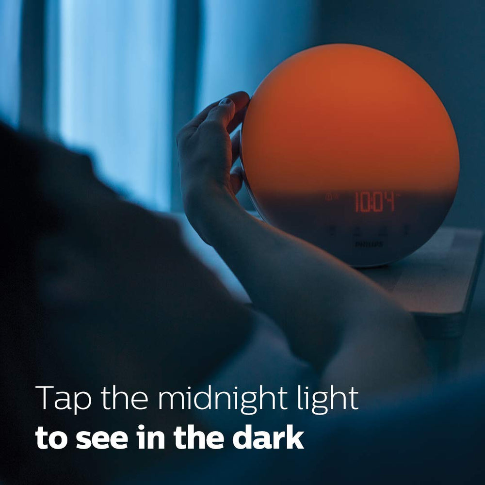 Philips SmartSleep junto a un libro y teléfono para comparar tamaño y escala, compacto en cabecera