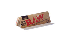 Mano enrollando con papel Raw 1 1/4 demostrando facilidad y sellado natural