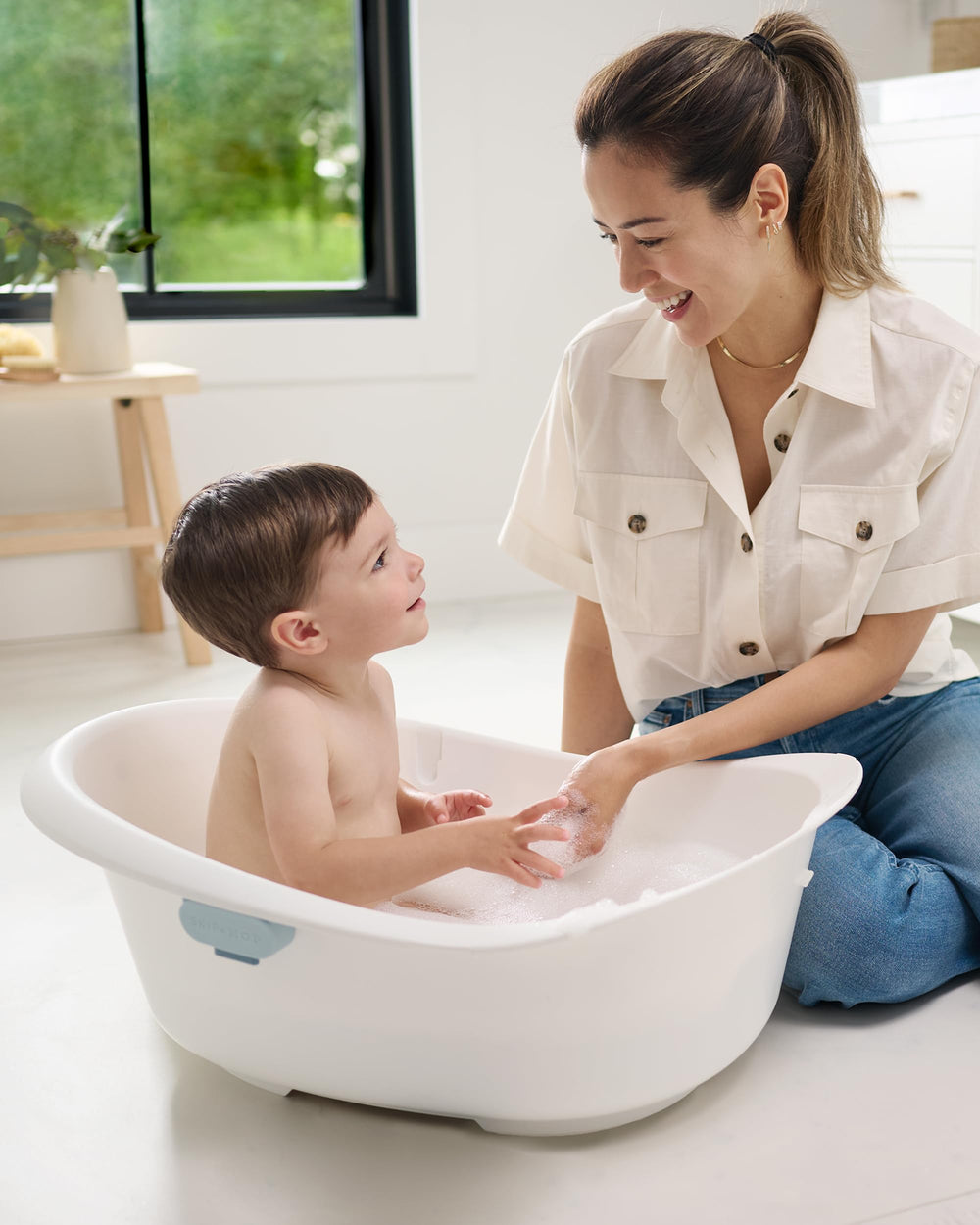 Skip Hop niño pequeño sentado en la bañera disfrutando con soporte estable