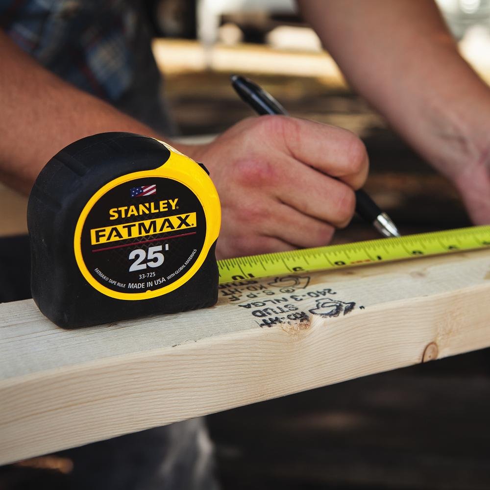 STANLEY FatMax en uso midiendo una viga, marcas de 16" y 19.2" visibles