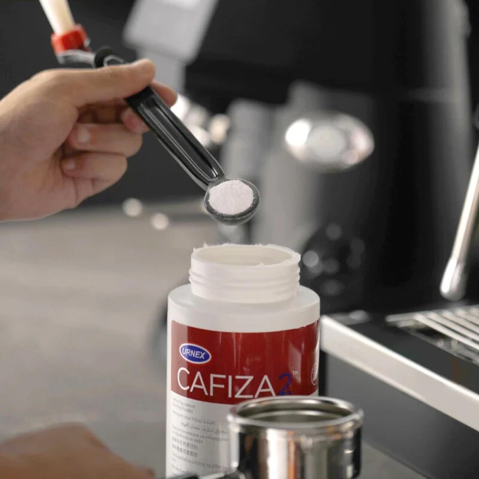 Urnex Cafiza polvo disuelto en agua creando espuma activa para eliminar aceites